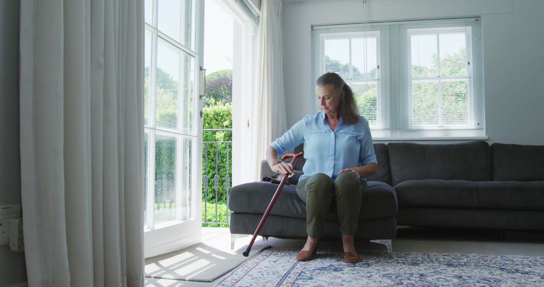 Senior Woman Sitting on Couch Using Cane at Home - Free Images, Stock Photos and Pictures on Pikwizard.com