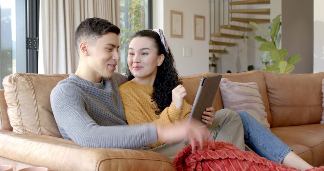 Young Couple Relaxing on Sofa Sharing Tablet in Modern Living Room
