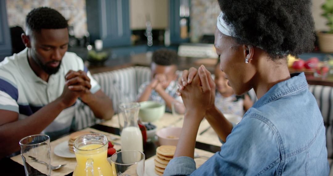 African American family praying before breakfast - Free Images, Stock Photos and Pictures on Pikwizard.com