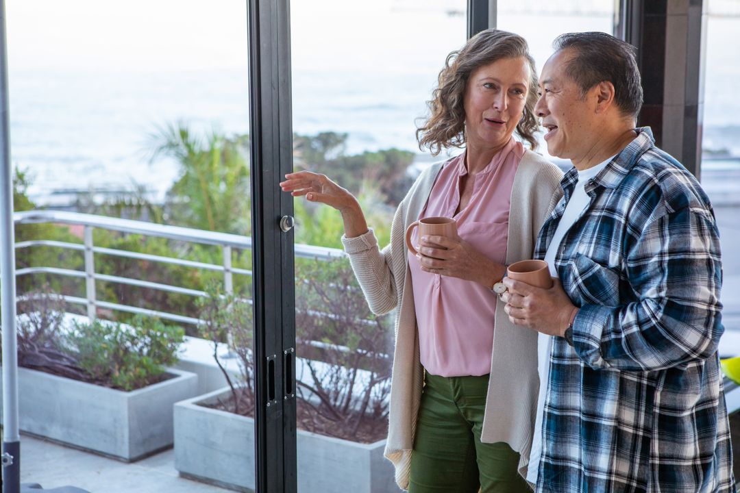 Senior Couple Enjoying Coffee by Ocean View in Modern Home