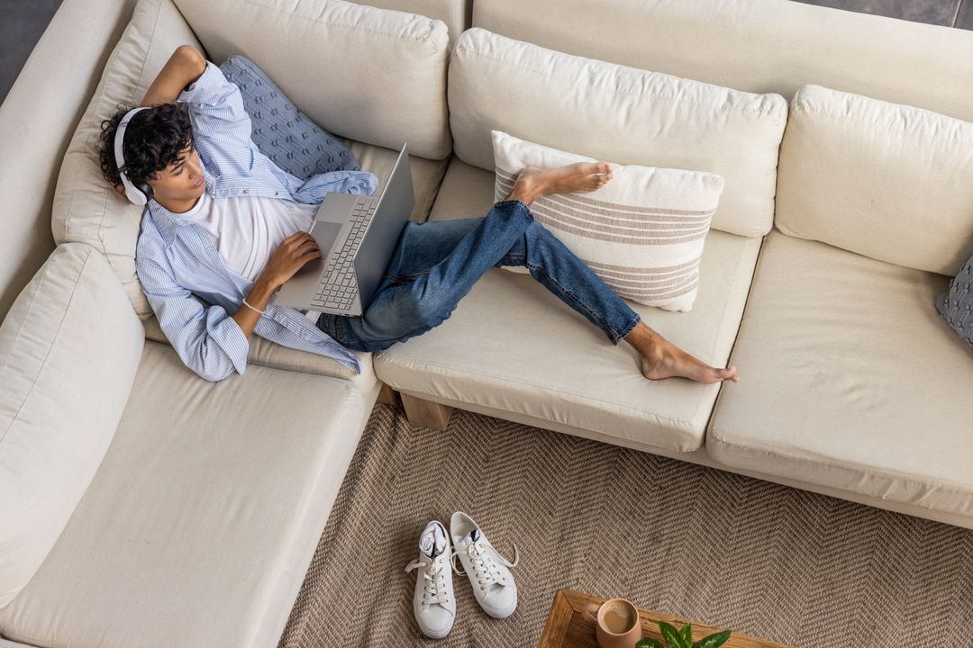 Relaxed Young Man Using Laptop on Comfortable Sofa at Home