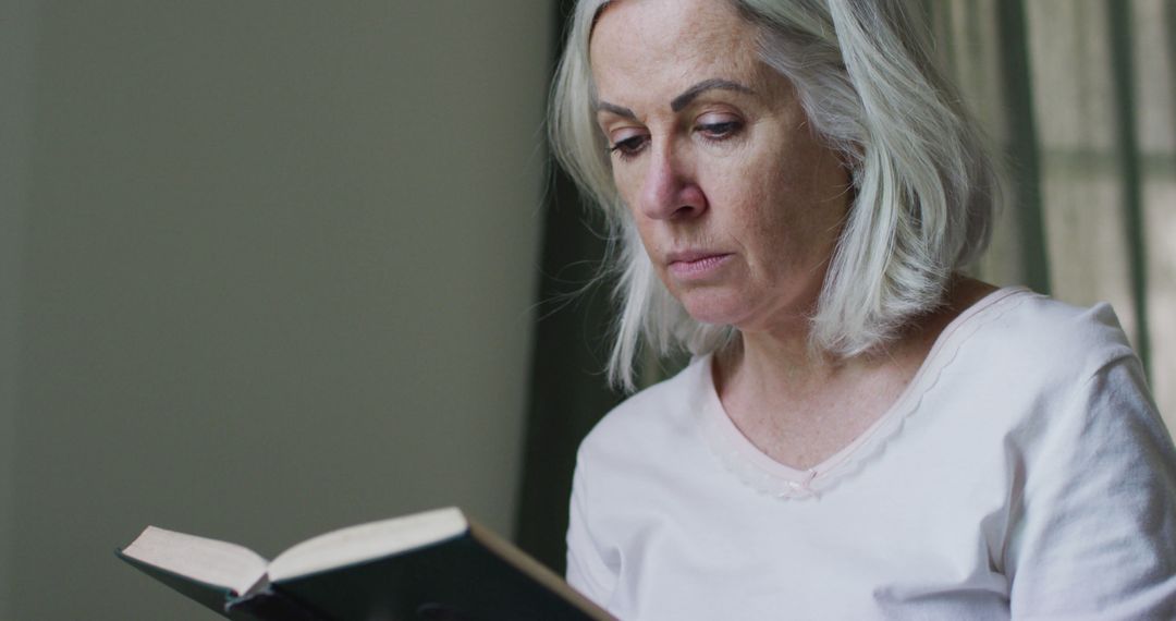 Focused Senior Woman Reading Book Indoors - Free Images, Stock Photos and Pictures on Pikwizard.com