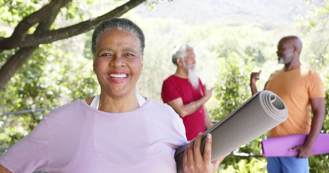 Happy Senior Woman Carrying Yoga Mat Outdoors with Friends in Background - Free Images, Stock Photos and Pictures on Pikwizard.com