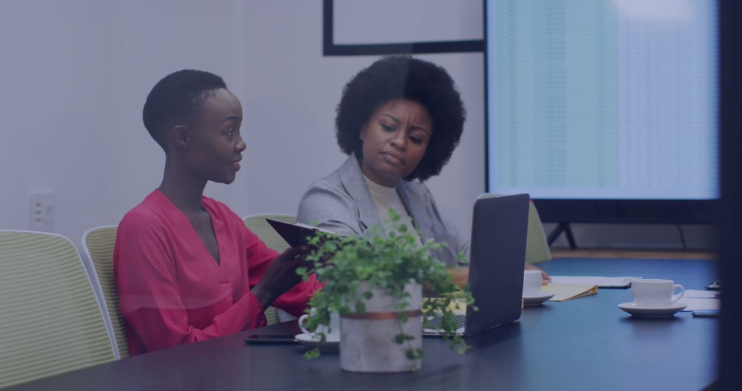 Diverse Colleagues Discussing Work at Conference Table with Technology