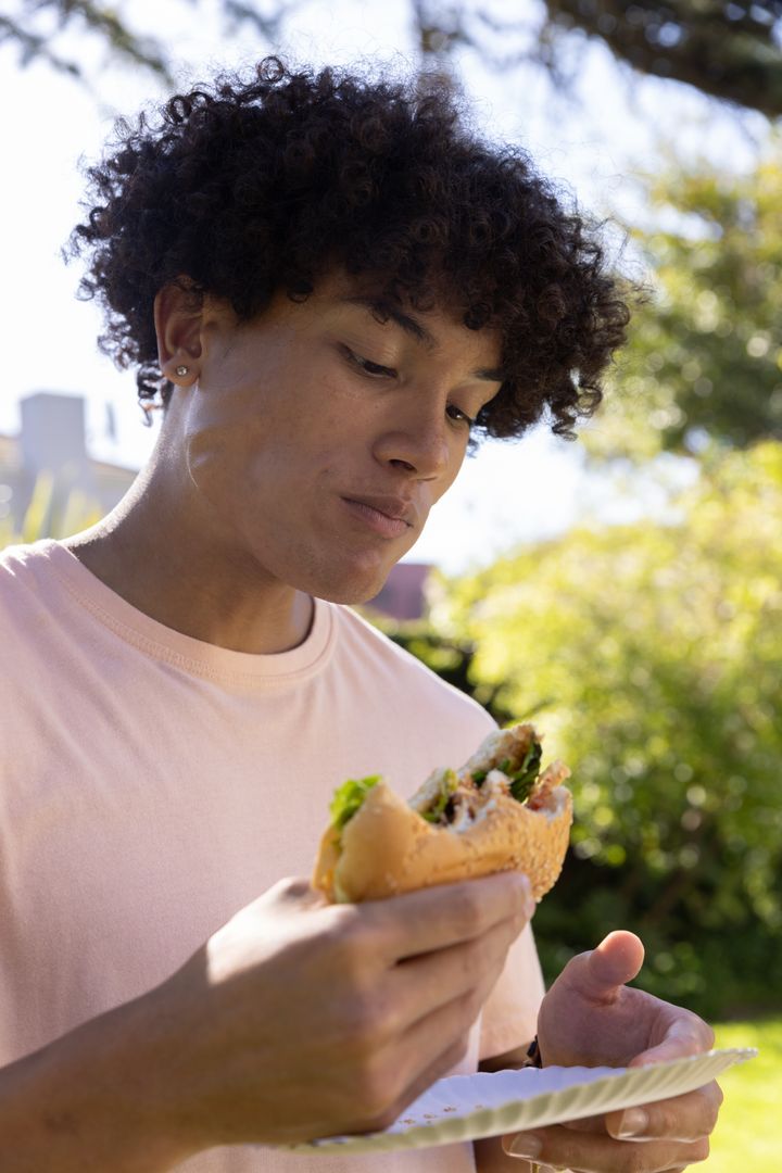 Man Enjoying a Fresh Sandwich Outdoors in a Garden