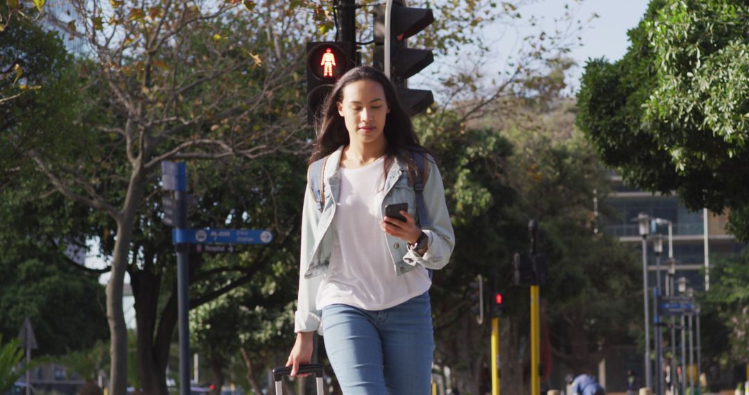 Young Woman Walking Outdoors Using Smartphone at Pedestrian Crossing - Free Images, Stock Photos and Pictures on Pikwizard.com