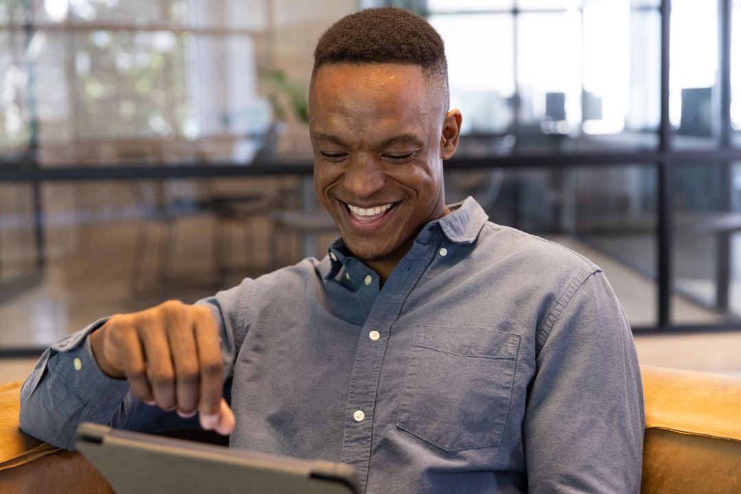 Smiling Man Using Tablet in Modern Workspace Lounge