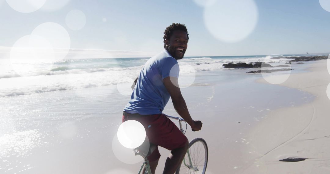 Joyful Man Cycling on Beach Shoreline in Radiant Sunlight