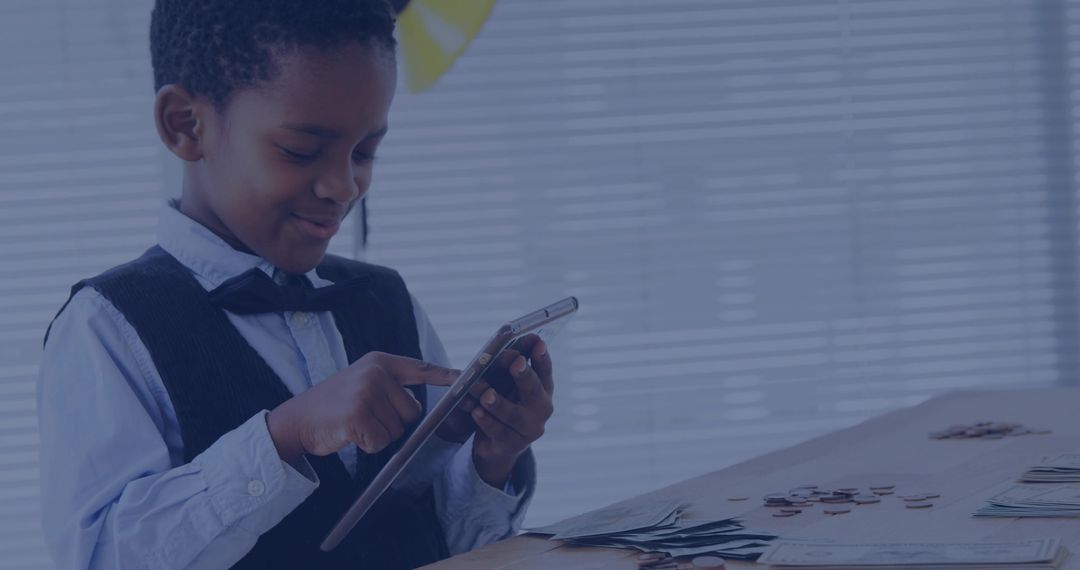 Boy calculating savings on tablet while sorting coins and cash at wooden desk