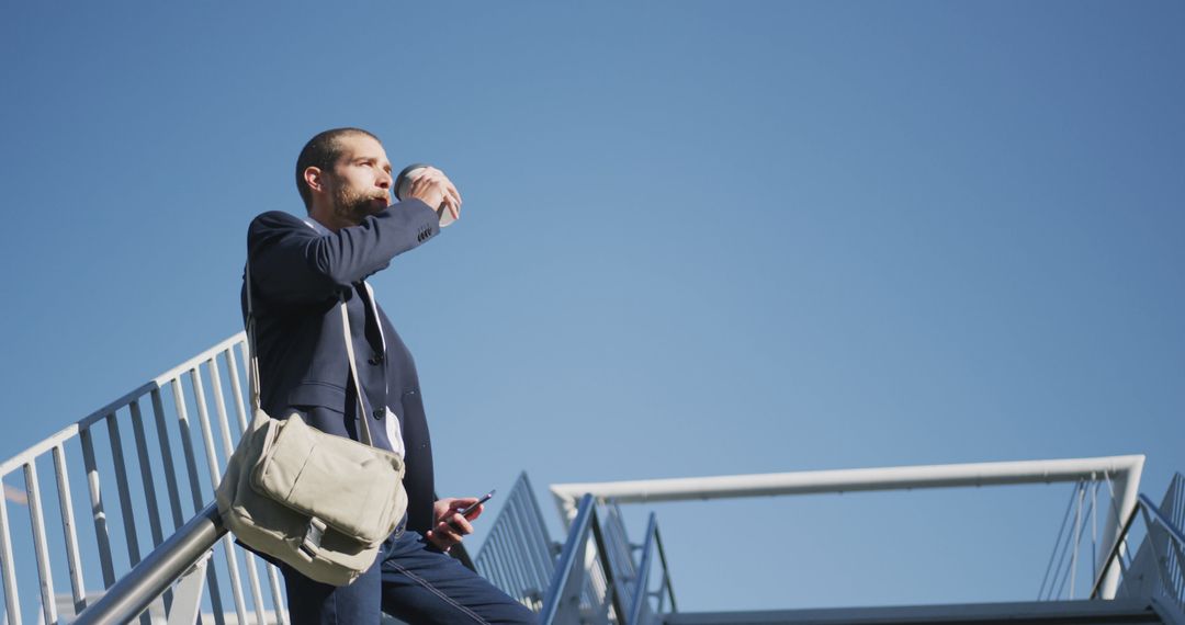 Businessman Drinking Coffee Outdoors Using Smartphone Under Clear Blue Sky - Free Images, Stock Photos and Pictures on Pikwizard.com