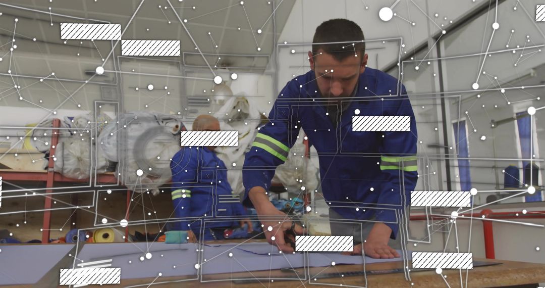 Textile worker cutting foam on workbench in hi-vis coveralls with digital network overlay