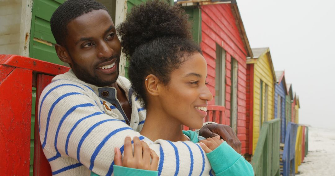 Happy couple embracing near colorful beach huts - Free Images, Stock Photos and Pictures on Pikwizard.com