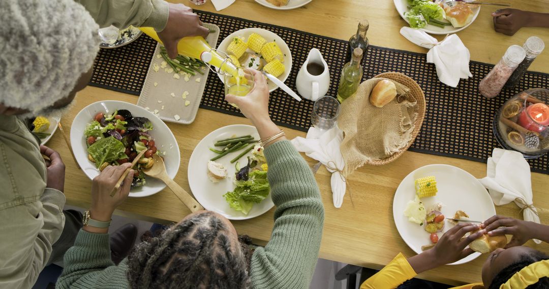 Multi-generational family sharing communal meal, passing salad and pouring juice at home