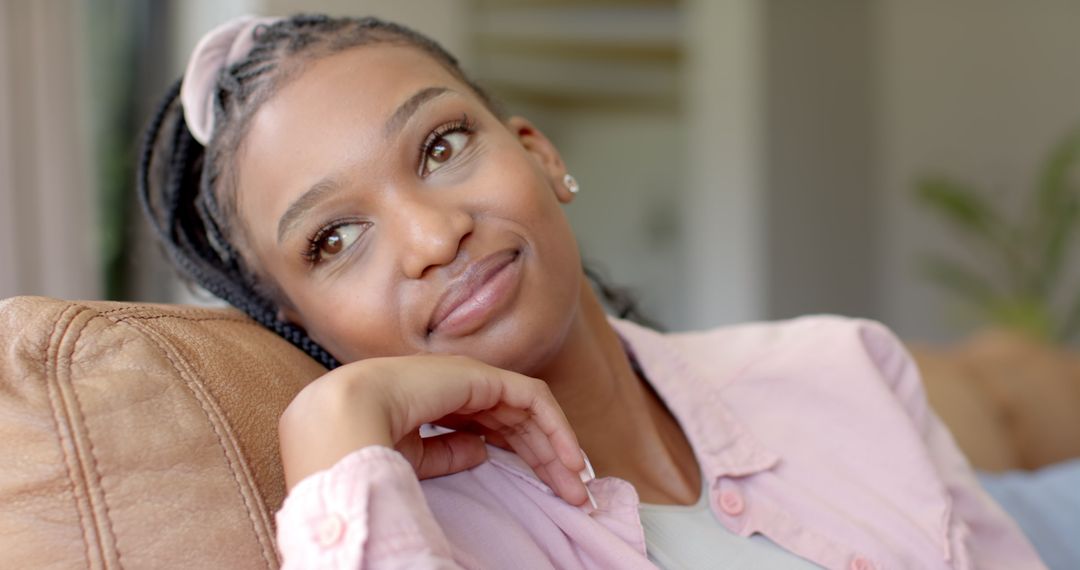 Relaxed Young Woman Daydreaming on Sofa with Serene Expression