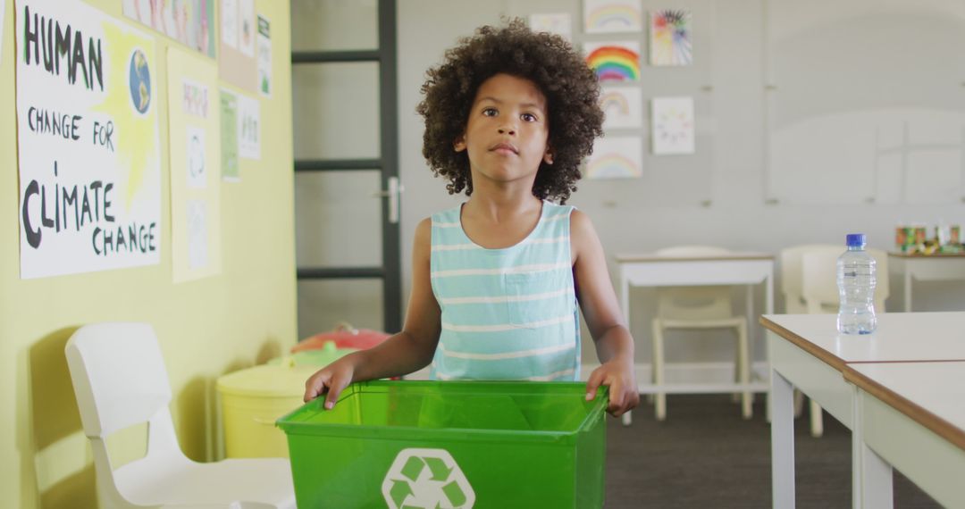Image of happy african american boy holding box with recycling symbol in classroom - Free Images, Stock Photos and Pictures on Pikwizard.com