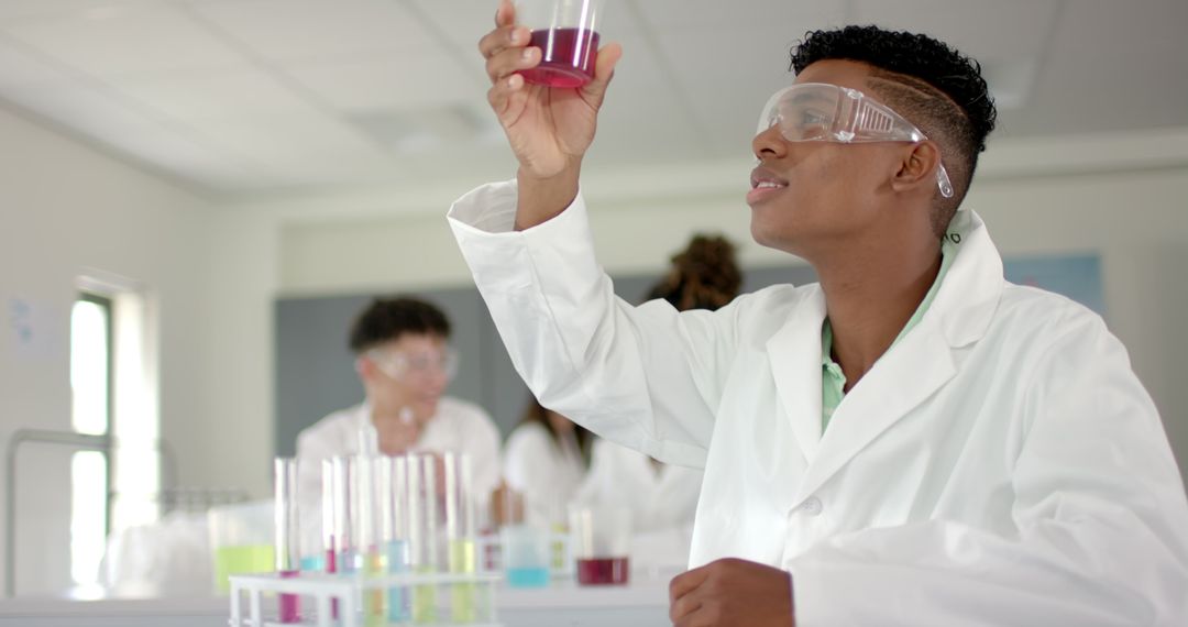 Teenage boy observing colorful reaction in chemistry lab experiment