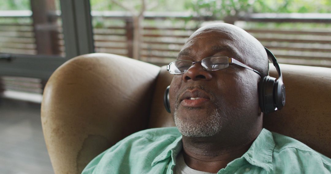 Happy african american senior man relaxing in armchair, wearing headphones and listening to music - Free Images, Stock Photos and Pictures on Pikwizard.com