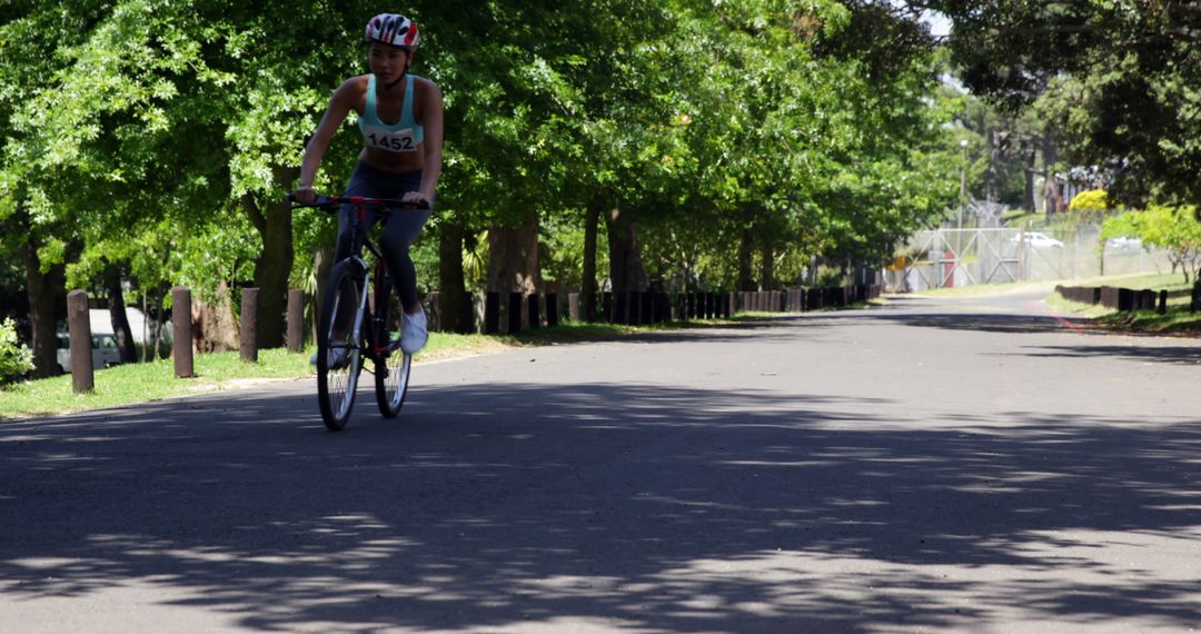 Female Cyclist Riding in Sunny Park with Bicycling Gear - Free Images, Stock Photos and Pictures on Pikwizard.com