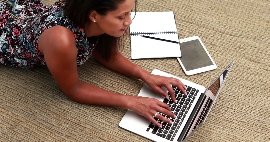 Woman Using Laptop on Carpet with Notebook and Tablet Nearby - Free Images, Stock Photos and Pictures on Pikwizard.com