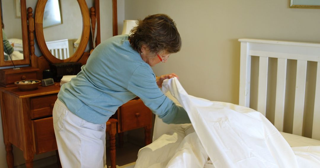 Elderly Woman Making Bed in Cozy Bedroom - Free Images, Stock Photos and Pictures on Pikwizard.com