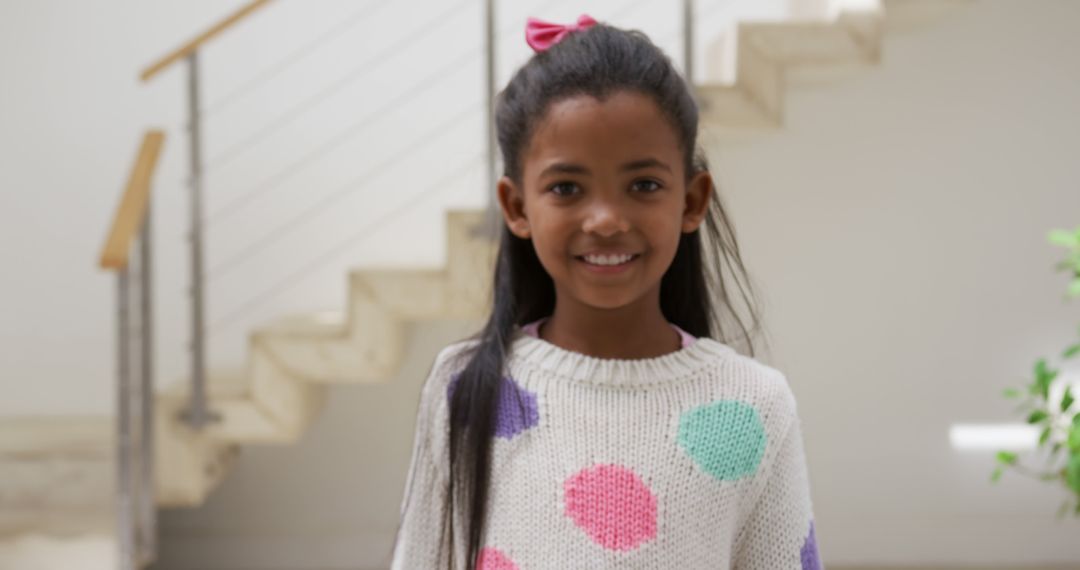 Smiling Girl in Polka Dot Sweater Standing in Modern Home Interior - Free Images, Stock Photos and Pictures on Pikwizard.com