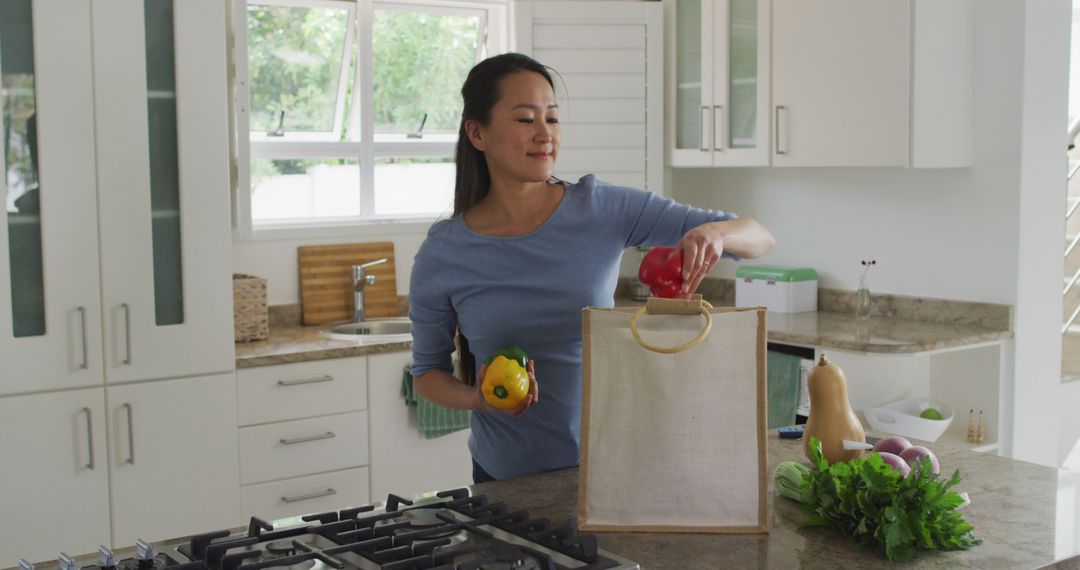 Woman in Modern Kitchen Putting Fresh Vegetables into Grocery Bag - Free Images, Stock Photos and Pictures on Pikwizard.com