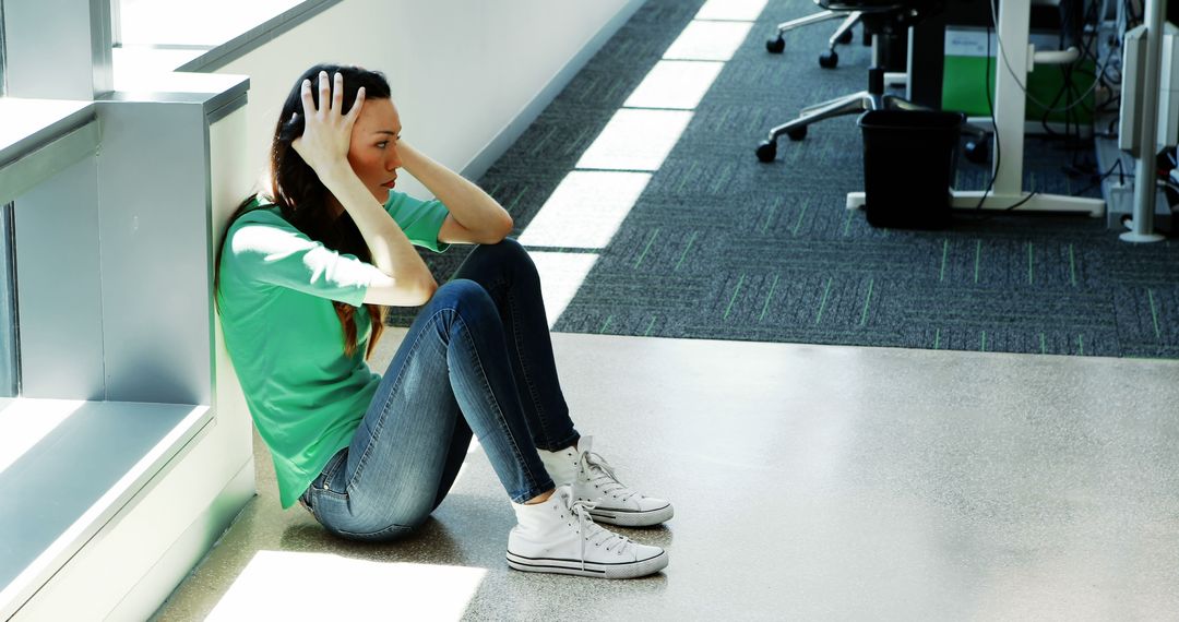 Young Woman Sitting on Floor Feeling Stressed or Anxious in Modern Office - Free Images, Stock Photos and Pictures on Pikwizard.com