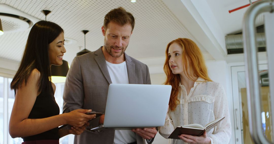 Caucasian Businessman Collaborates with Young Women in Modern Office - Free Images, Stock Photos and Pictures on Pikwizard.com