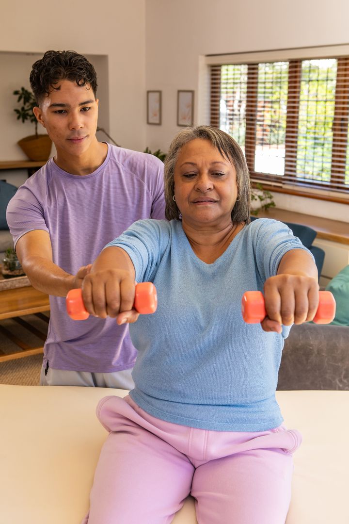 Personal Trainer Assisting Senior with Dumbbell Workout at Home
