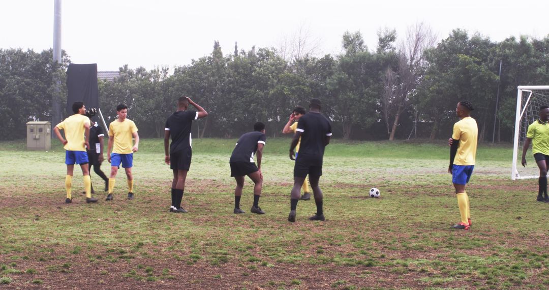 Diverse Soccer Team Strategizing on Muddy Field for Goal