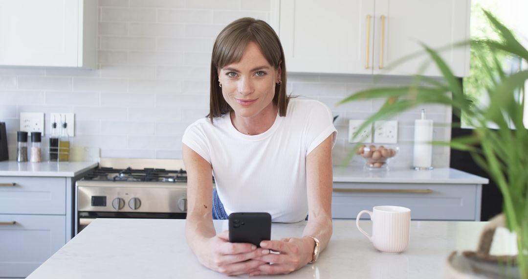 Caucasian Woman Starting Morning in Modern Kitchen with Smartphone