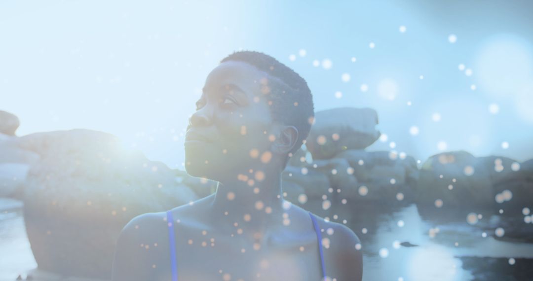 Woman Walking on Rocks With Ethereal Lights by Sea