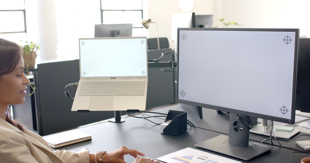 Professional Businesswoman Multitasking with Laptop and Desktop in Modern Office