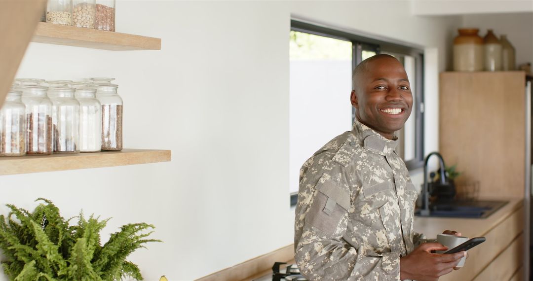 Smiling Soldier in Modern Kitchen Using Smartphone