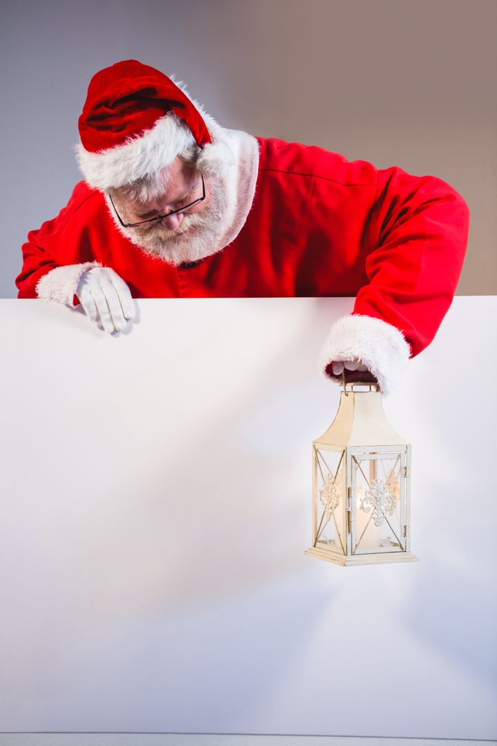 Santa Claus holding christmas lantern on white board - Free Images, Stock Photos and Pictures on Pikwizard.com