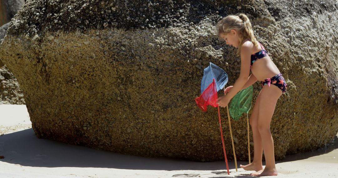 Young Girl Playing on Beach with Fishing Nets by Large Rock - Free Images, Stock Photos and Pictures on Pikwizard.com