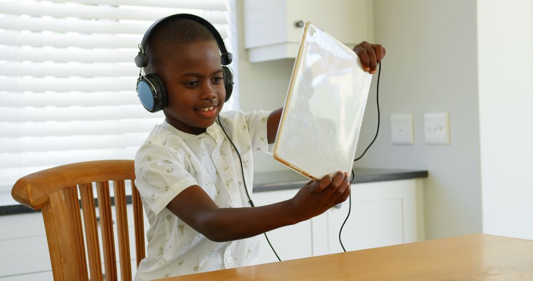 Young Boy Wearing Headphones Enjoying Game on Tablet