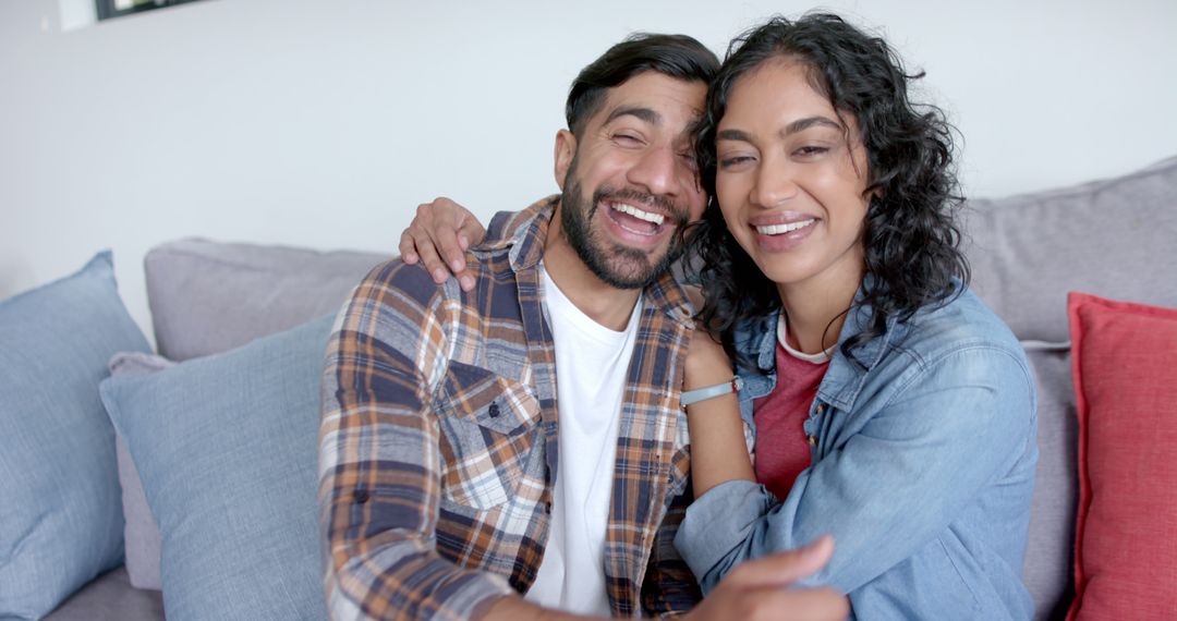 Smiling Biracial Couple Embracing on Sofa at Home