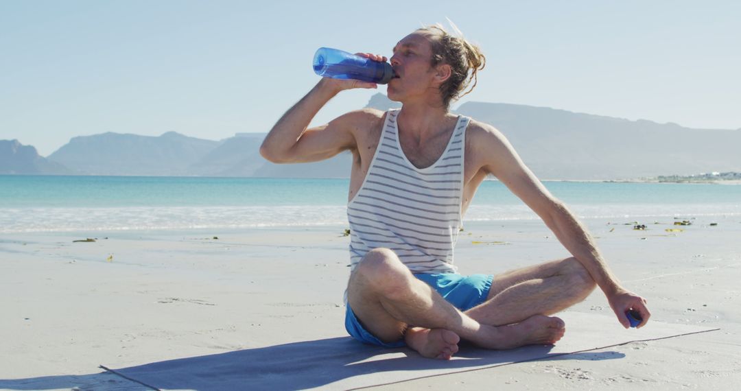 Man Drinking Water While Doing Yoga on Beach - Free Images, Stock Photos and Pictures on Pikwizard.com