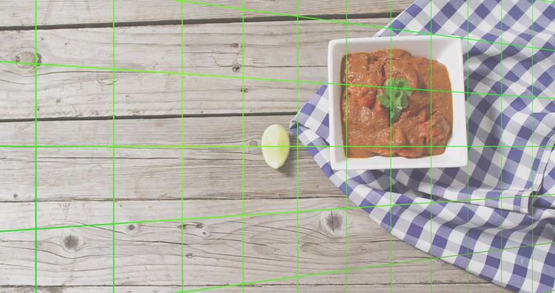 Square bowl of tomato dip garnished with cilantro on gingham cloth over rustic wood planks