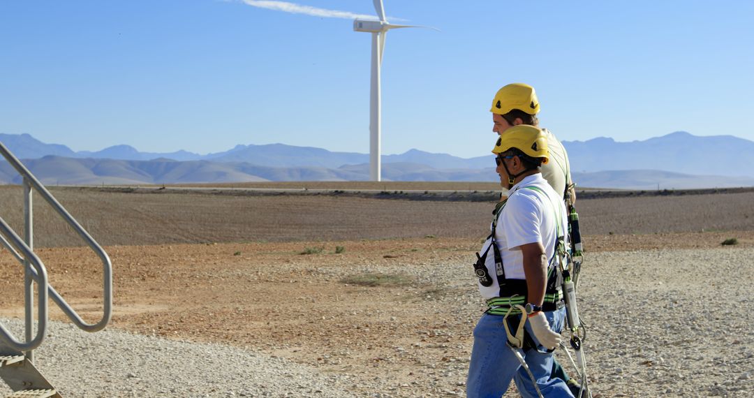 Workers Wearing Safety Gear Walking Near Wind Turbine in Rural Area - Free Images, Stock Photos and Pictures on Pikwizard.com