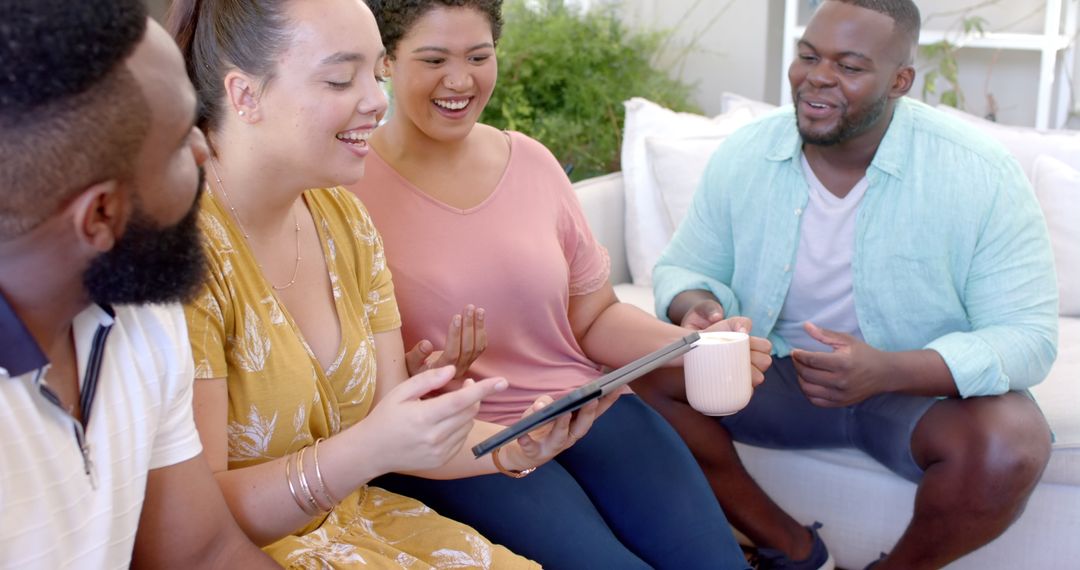 Diverse Friends Socializing Using Tablet And Enjoying Coffee At Home