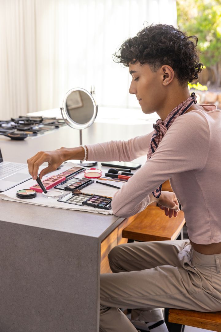 Man Applying Eyeshadow at Modern Kitchen Island with Laptop