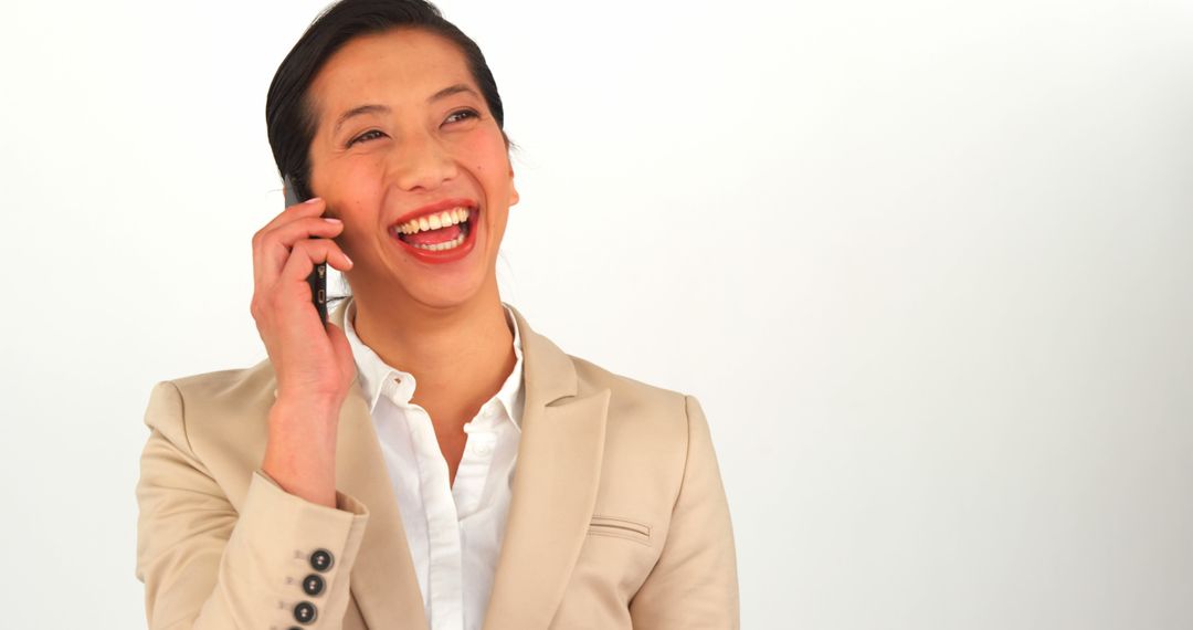 Businesswoman Smiling and Talking on Phone in Beige Suit - Free Images, Stock Photos and Pictures on Pikwizard.com