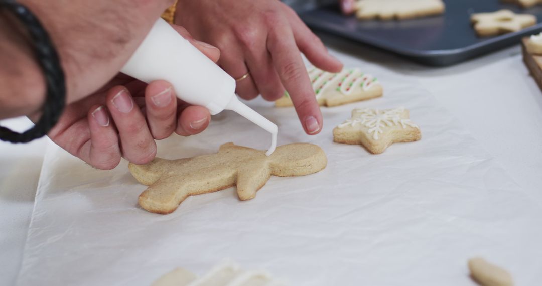 Hands Decorating Christmas Cookies with Icing in Festive Atmosphere