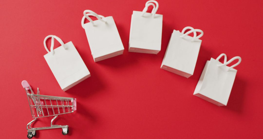 Five white gift bags and shopping trolley on red background with copy space - Free Images, Stock Photos and Pictures on Pikwizard.com