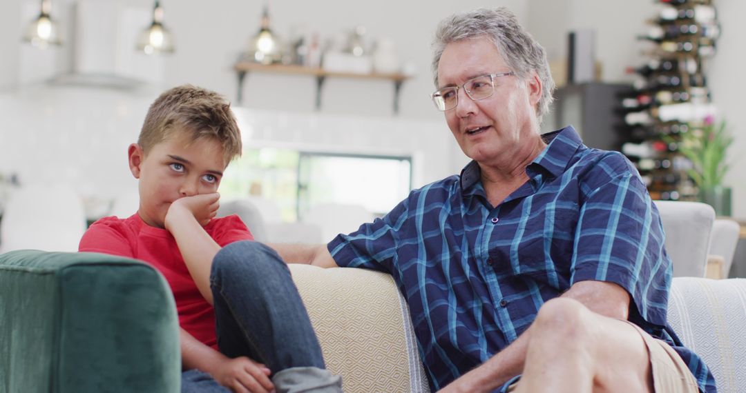 Grandfather Sitting with Uninterested Grandson on Couch - Free Images, Stock Photos and Pictures on Pikwizard.com