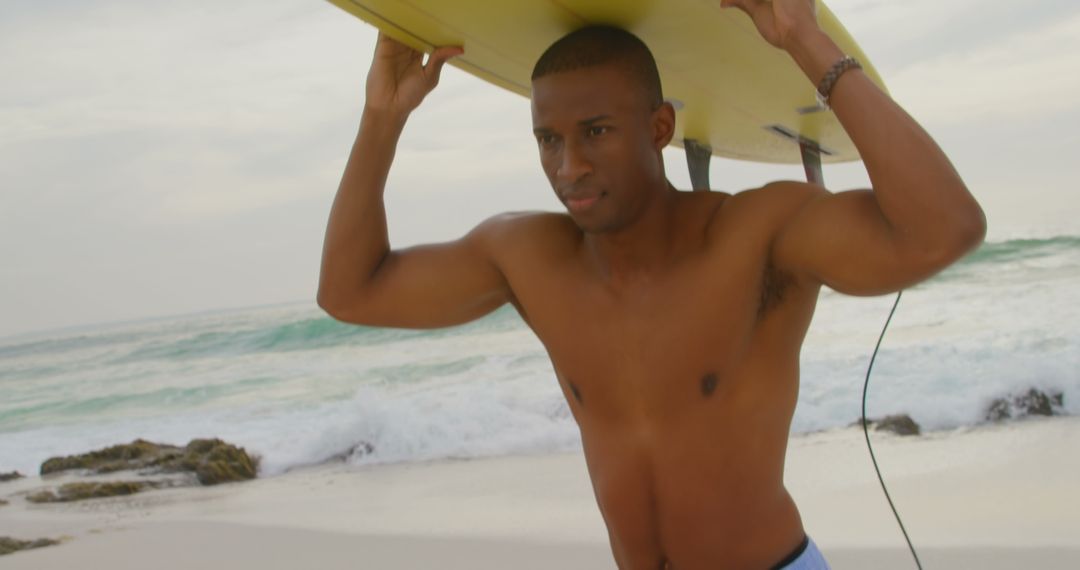 Confident Surfer Carrying Board at Beach Edge with Ocean Waves