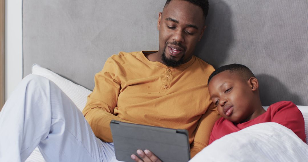 Father and Son Enjoying Tablet Time in Cozy Bed