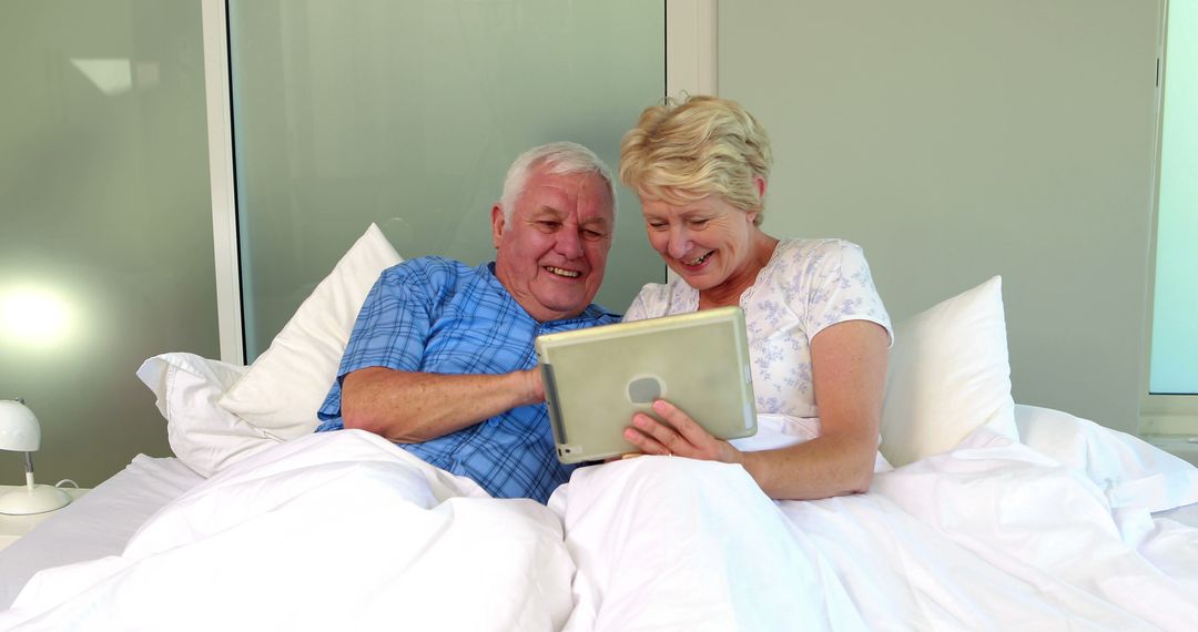 Happy Senior Couple Using Tablet in Bed - Free Images, Stock Photos and Pictures on Pikwizard.com